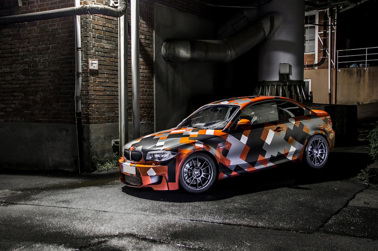 bachelor-party-02 Eye-catching camo-wrapped car parked in an industrial area at night, showcasing vibrant colors and sleek design.