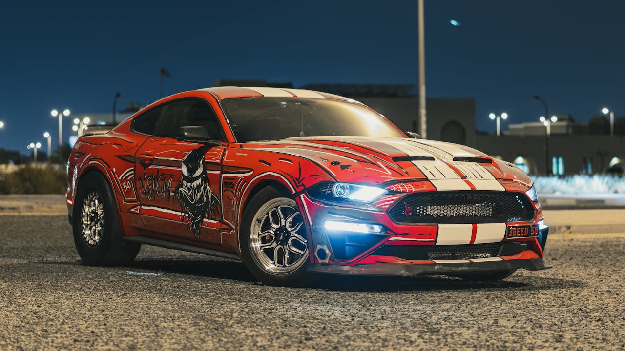 bachelor-party-03 Custom Ford Mustang showcasing a striking red livery parked in an urban setting at night.
